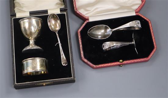 A cased childs silver pusher and similar egg cup spoon and napkin ring.